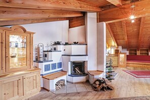 A rustic kitchen with wooden beams, a fireplace, and a built-in cabinet with glass doors. - Chalet Tiroler Straße (Reit im Winkl)