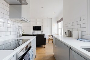 Eine moderne Küche mit weißen Schränken, einem eingebauten Ofen und einer Kaffeemaschine auf der Arbeitsplatte.