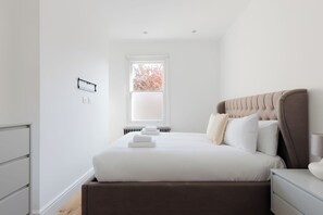 Ein Schlafzimmer mit Bett, Fenster, Heizkörper und Nachttisch.