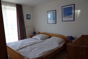 A single bed with a wooden frame, two pillows, and a nightstand with a lamp. - Holiday home with 4 bedrooms (Wangerooge)