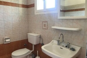 Un baño con inodoro, lavabo y ventana.