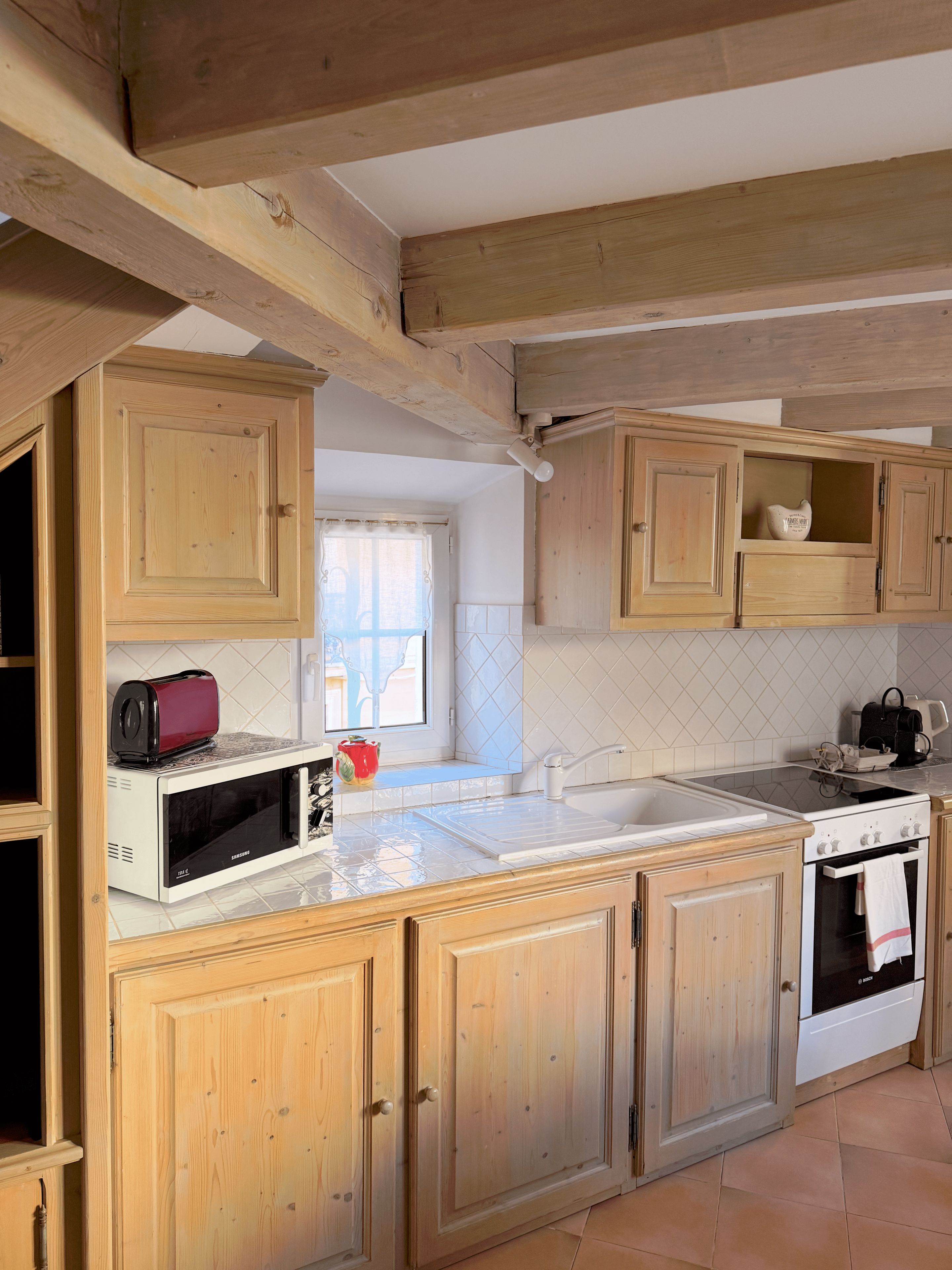 Une cuisine avec des meubles de rangement en bois, un four à micro-ondes, un grille-pain et un évier.