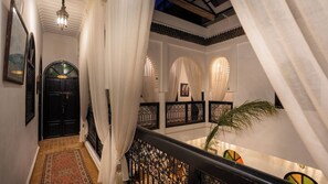 A corridor with a black door, white curtains, and a staircase with black railings. - Riad Dabachi (Marrakech)