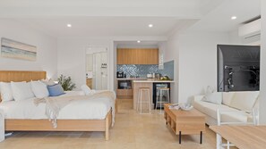 A modern hotel room with a bed, a sofa, a small kitchen area, and a dining table. - Seascape Studio in Terrigal (Terrigal)