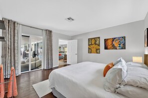 A hotel room with a large bed, a sliding glass door leading to a balcony, and two paintings on the wall. - Sun, Pool & Sand- Fort Lauderdale Style Escape! (Fort Lauderdale)