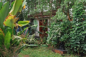 A lush garden with a variety of plants and a small structure with a roof. - Bougainvillea by Stayjade Poolbonfire Mysore Rd (Channapatna)