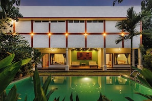 A hotel with a pool, a covered seating area, and a well-lit facade.