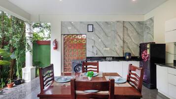 Een eethoek met een tafel voor vier personen, een wasmachine en een koelkast op de achtergrond.