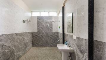 A bathroom with a sink, mirror, and shower area.