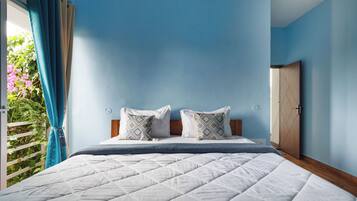 A bedroom with a bed, two pillows, a bedside table, a clock, and a door.