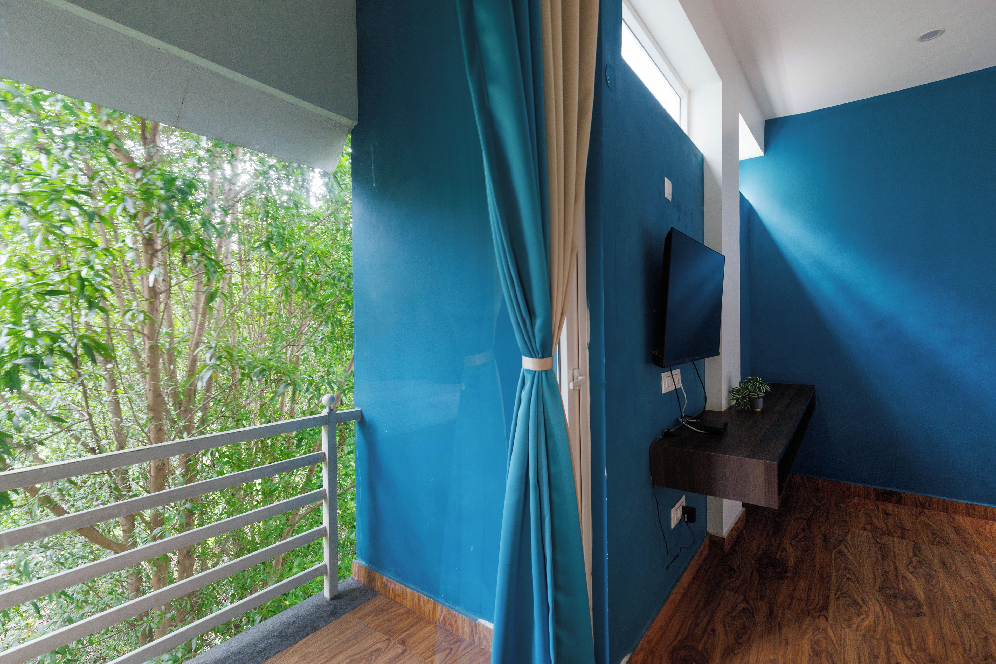 Een kamer met balkon, een aan de muur bevestigde televisie en een houten vloer.