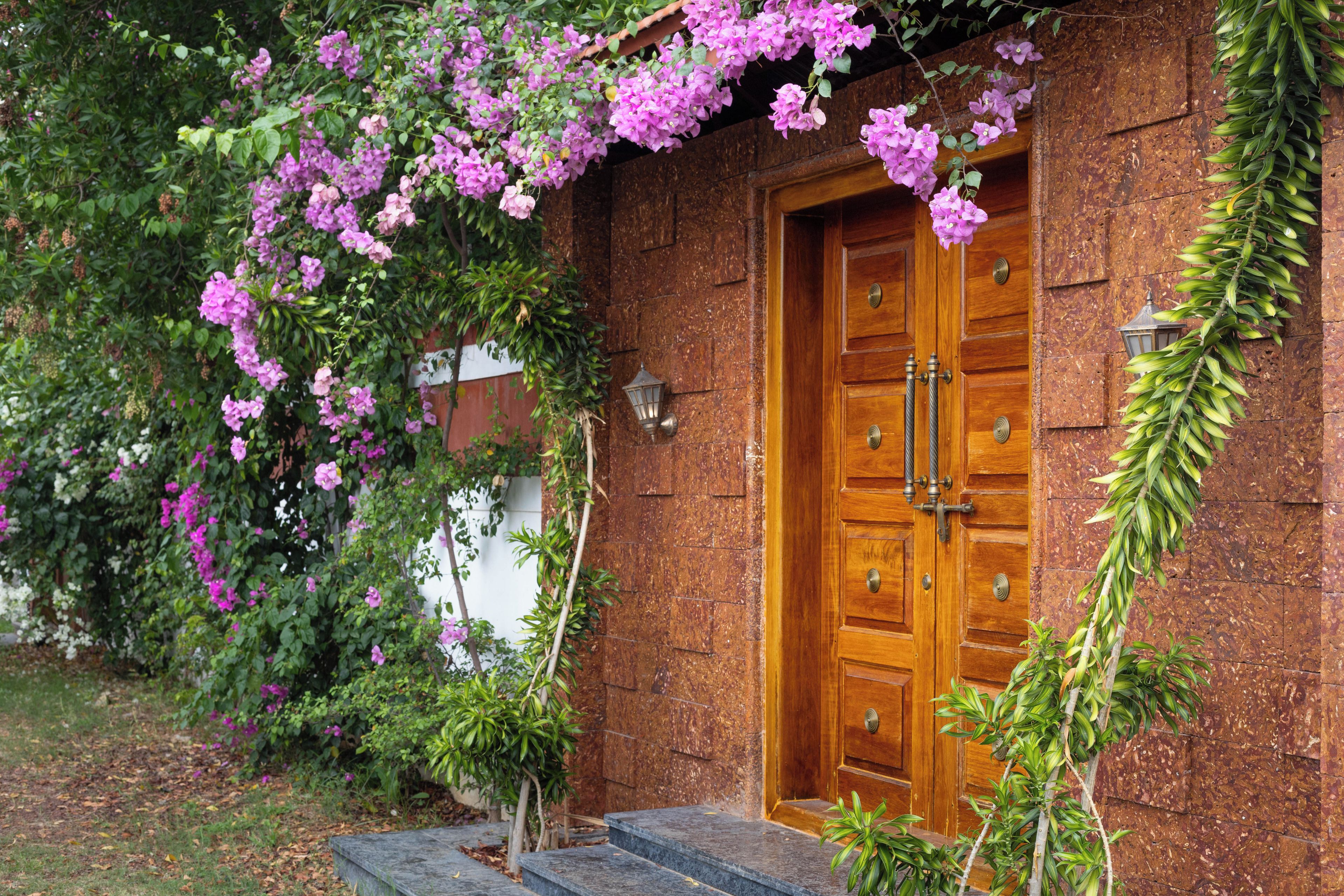Une porte en bois avec une poignée en laiton, un mur en pierre et un escalier en bois menant à l’entrée.