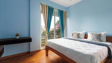 Un dormitorio con cama, mesita de noche, ventana con cortinas y vista al exterior.