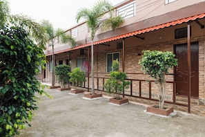 A building with a brick facade, multiple windows, and a covered walkway with planters.