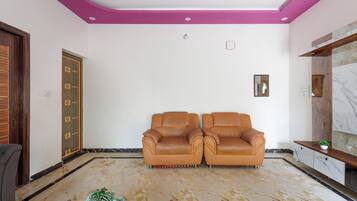 A room with two leather sofas, a wooden door, and a marble floor.