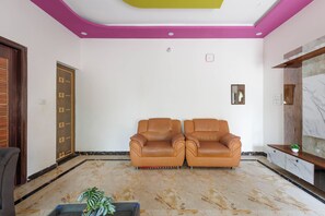A room with two leather sofas, a wooden door, and a marble floor.