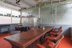 A long wooden table with chairs, a refrigerator, and a tiled backsplash. - White Swan by Stayjadepoolbbqbonfire Mysore Rd (Ramanagara)