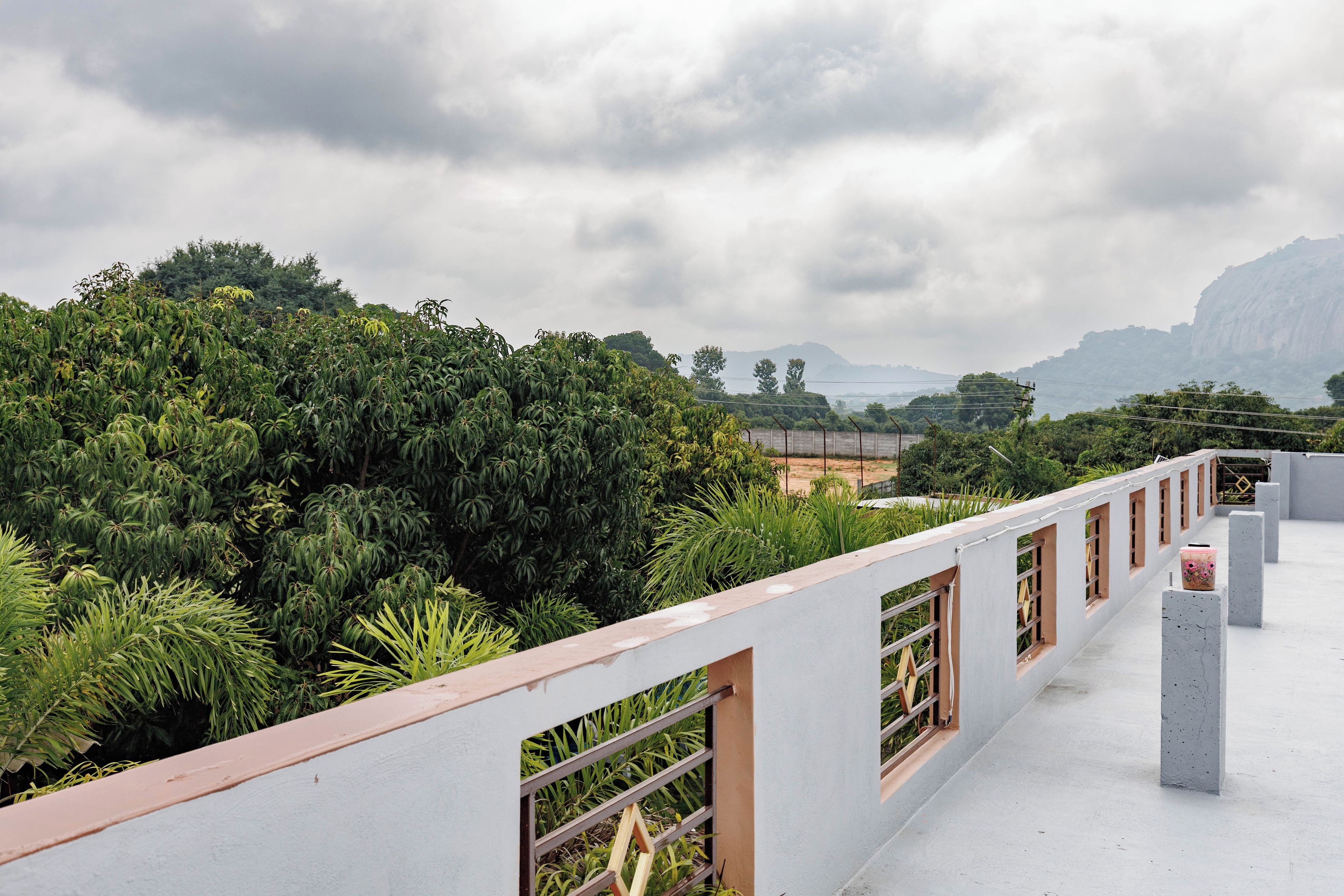 A rooftop terrace with a view of dense greenery and distant mountains.
