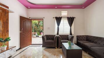 A living room with a sofa set, a glass coffee table, and a wooden door.