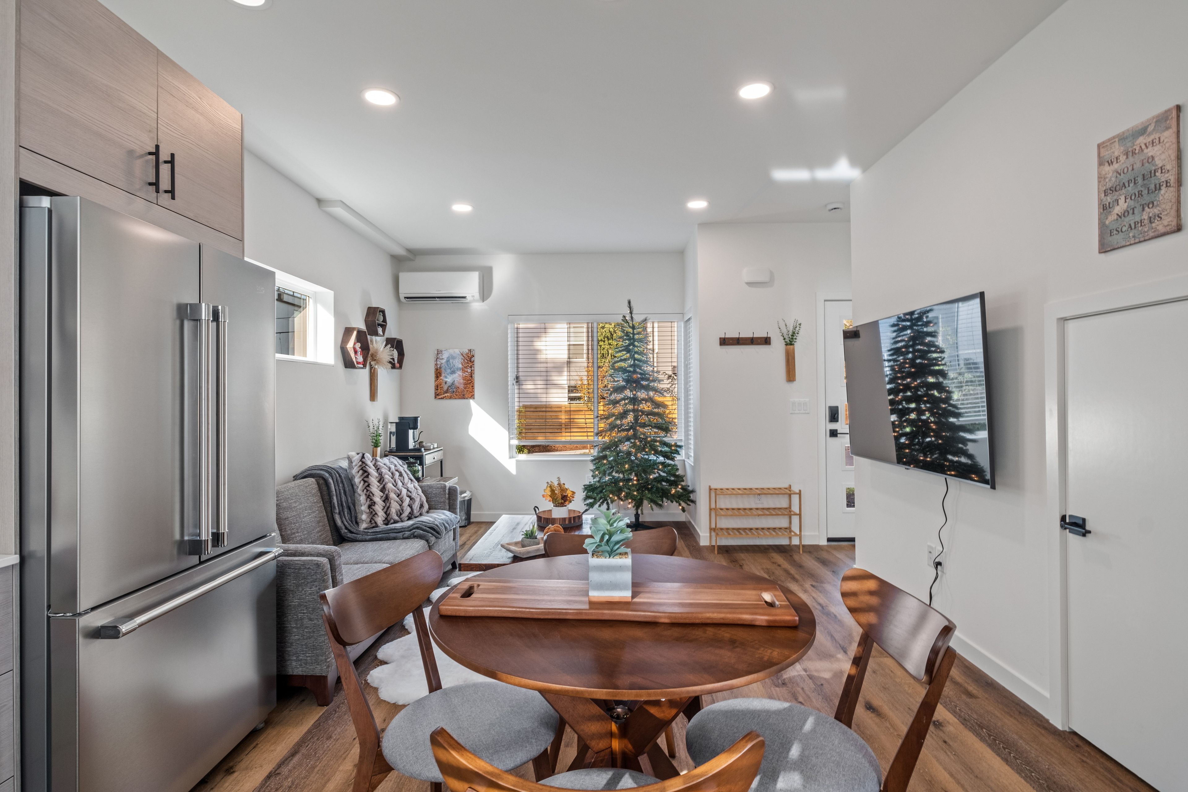 A modern kitchen with a dining area, a refrigerator, and a Christmas tree.
