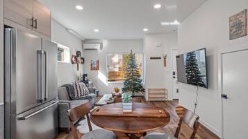 A modern kitchen with a dining area, a refrigerator, and a Christmas tree.