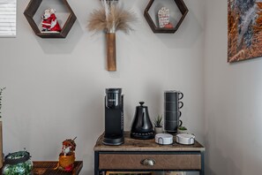 Un coin café avec une machine à café Keurig, une cafetière à piston et une tasse sur une table en bois.