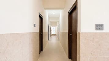 Un pasillo con puertas a ambos lados, un interruptor de luz en la pared y un suelo de baldosas.