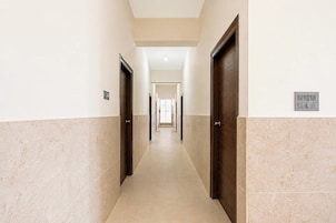 Un pasillo con puertas a ambos lados, un interruptor de luz en la pared y un suelo de baldosas.