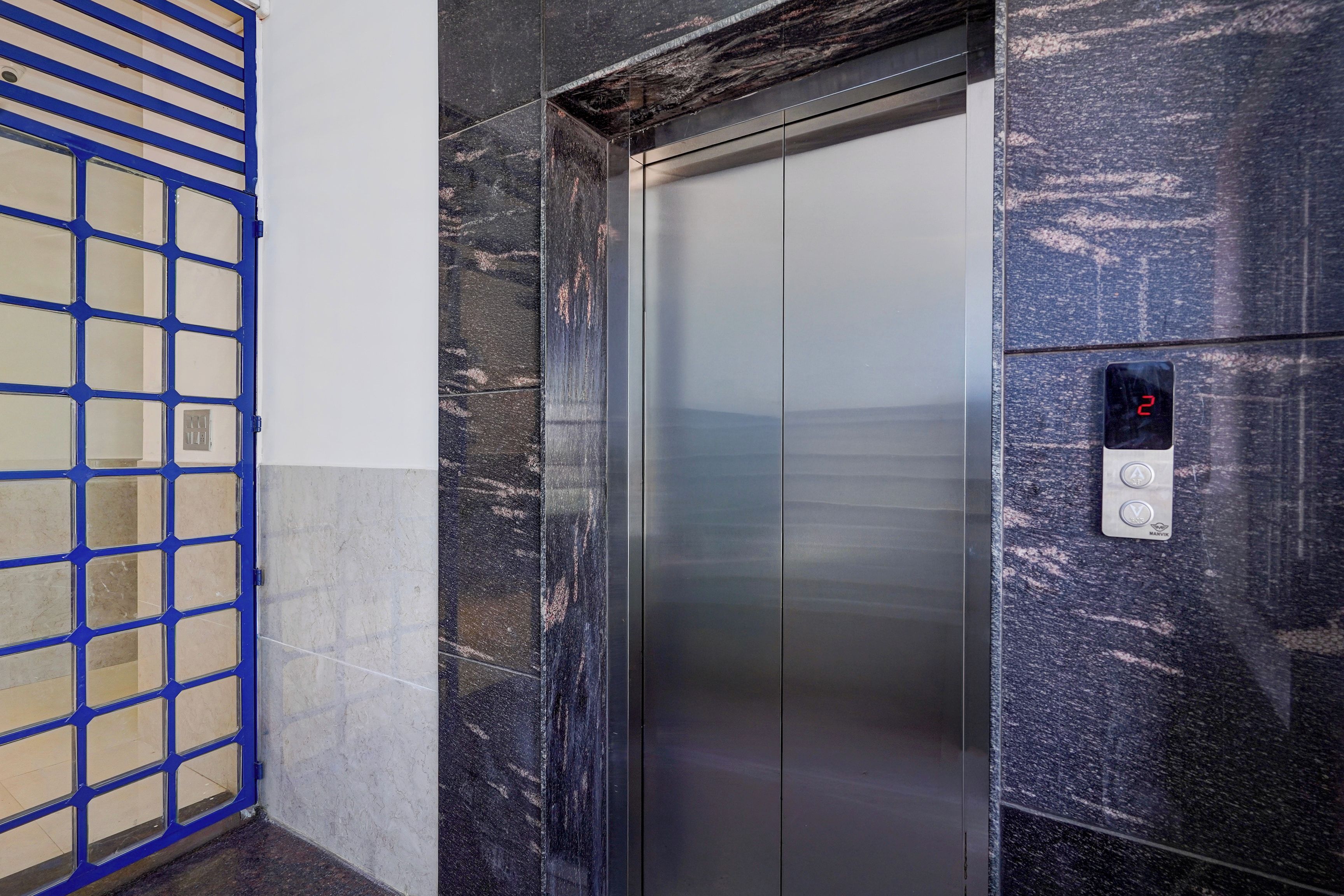 An elevator with a digital display showing the number 2, a metallic door, and a blue metal gate to the left.