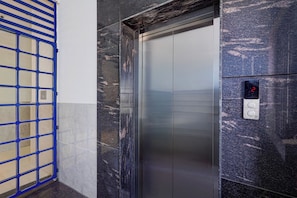 An elevator with a digital display showing the number 2, a metallic door, and a blue metal gate to the left.