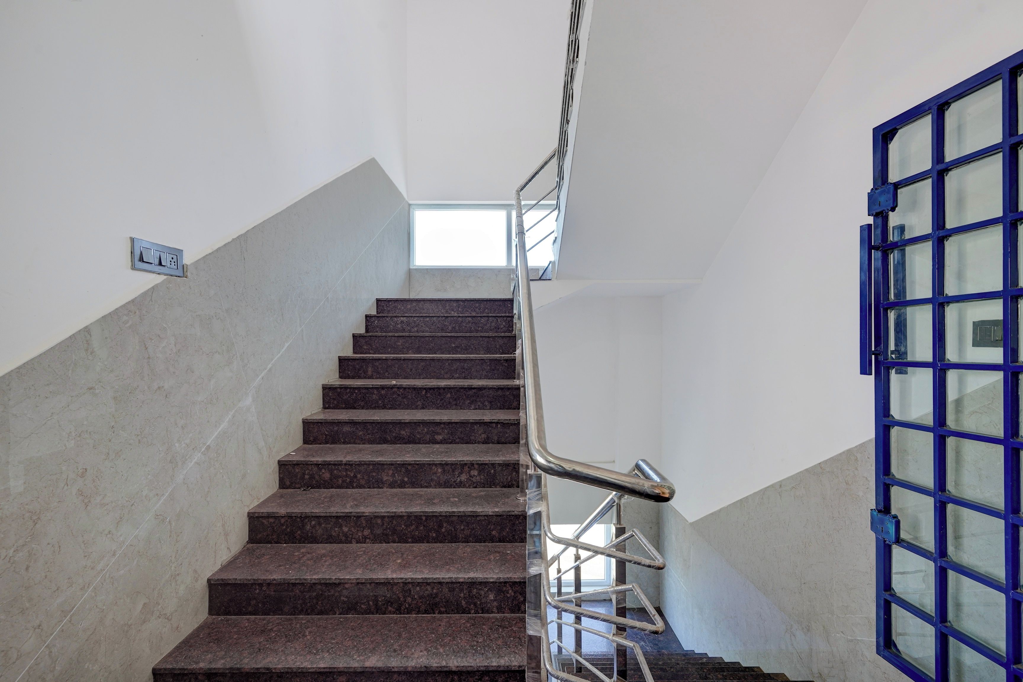 A staircase with a metal handrail and a blue door at the bottom.