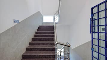 A staircase with a metal handrail and a blue door at the bottom.