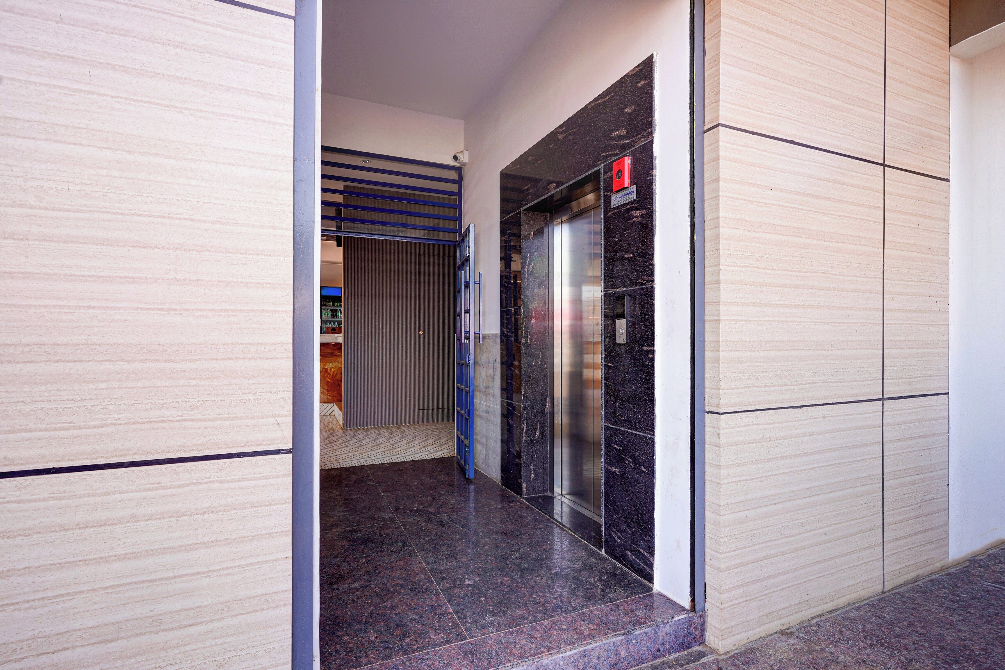 Un pasillo con un ascensor cerrado y una puerta que da a una habitación con piso de baldosas.