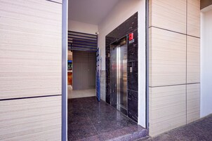 Un pasillo con un ascensor cerrado y una puerta que da a una habitación con piso de baldosas.