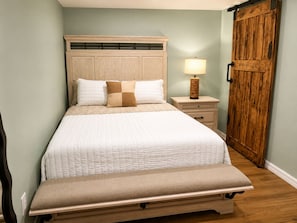 Ein Schlafzimmer mit einem Bett, einem Nachttisch, einer Lampe und einem Holzschrank.