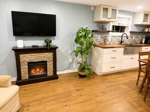 Una sala de estar con chimenea, televisor de pantalla plana y comedor con mesa y sillas de madera.