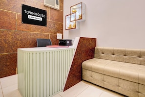 A reception area with a wooden wall, a reception desk, a sofa, and a framed picture. - Townhouse Durgakund Temple Varanasi (Varanasi)