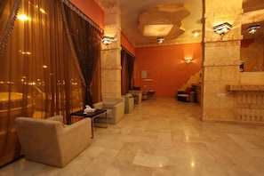A lobby with a seating area, a reception desk, and a stone wall with a carved design.