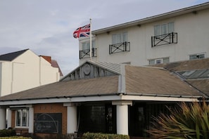 A building with a flag, a sign that reads 'ON THE FRONT', and a balcony.