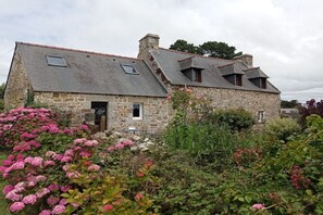 Ein Steinhaus mit geneigtem Dach und mehreren Fenstern.