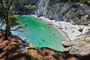 Ett kustområde med klart, turkosfärgat vatten, klippiga branter och en sandstrand.
