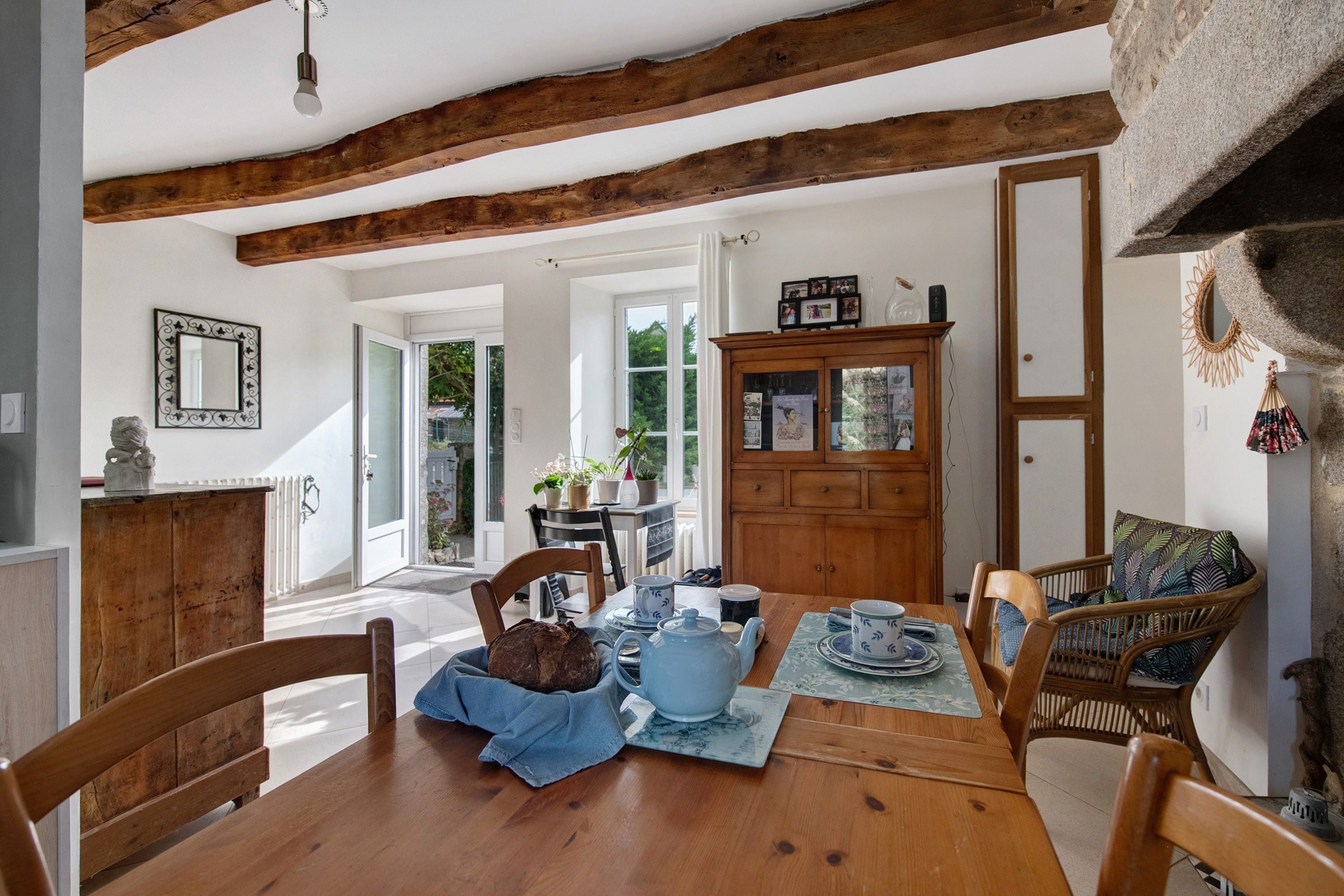 Un comedor con una mesa de madera, sillas y un mueble con puertas de cristal.