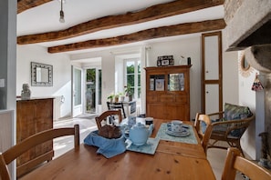 Un comedor con una mesa de madera, sillas y un mueble con puertas de cristal.