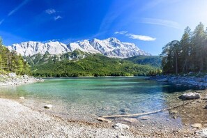 A mountain lake with clear water, surrounded by forested mountains and rocky shores. - Holiday apartment with 1 bedroom (Garmisch-Partenkirchen)