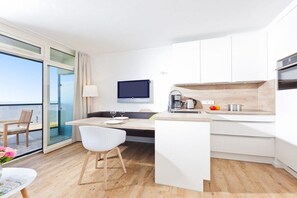 Cozinha moderna com área de refeições, televisão de tela plana e vista para o mar.