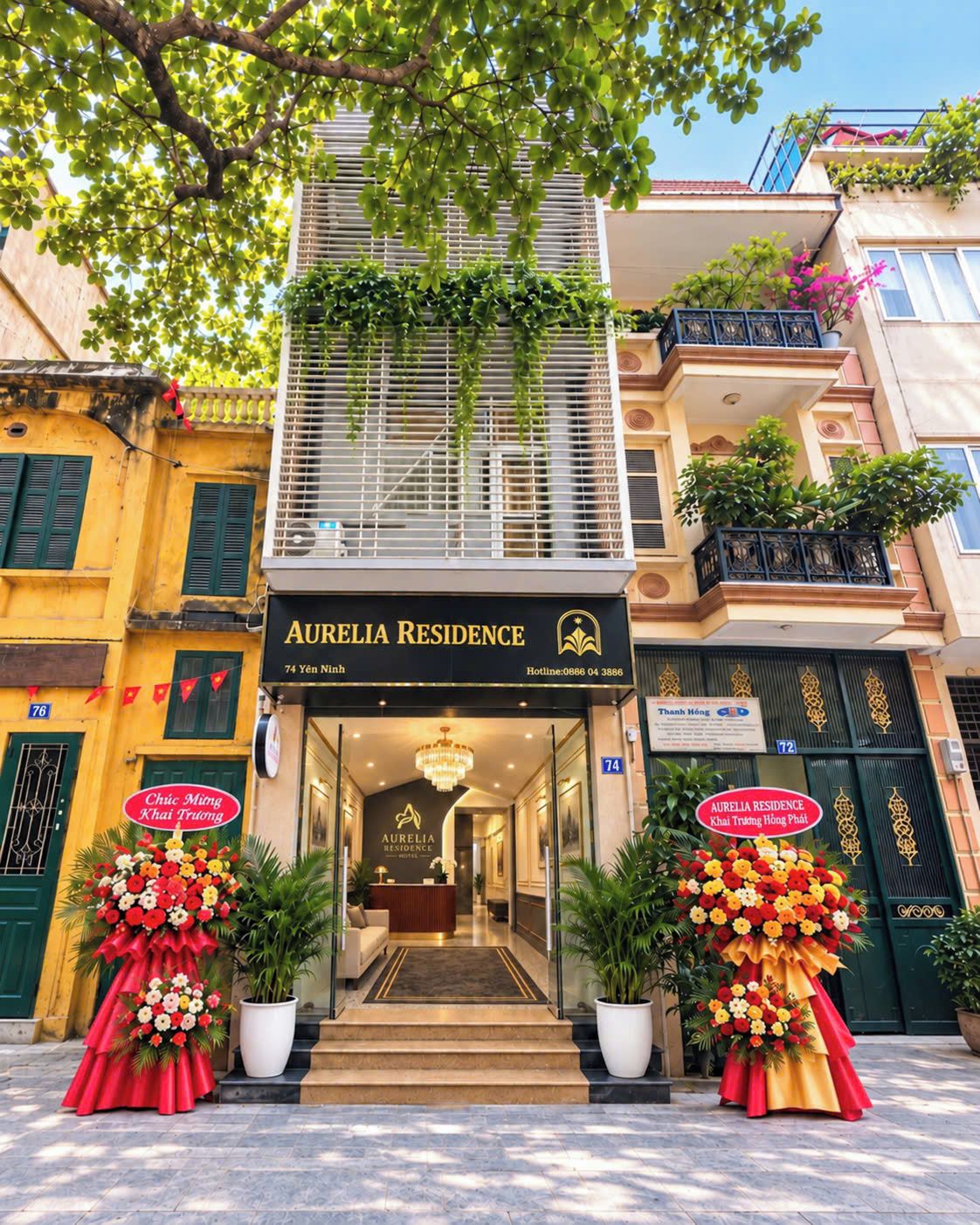 L’entrée d’un hôtel, avec un comptoir de réception, un lustre et deux grands arrangements floraux.