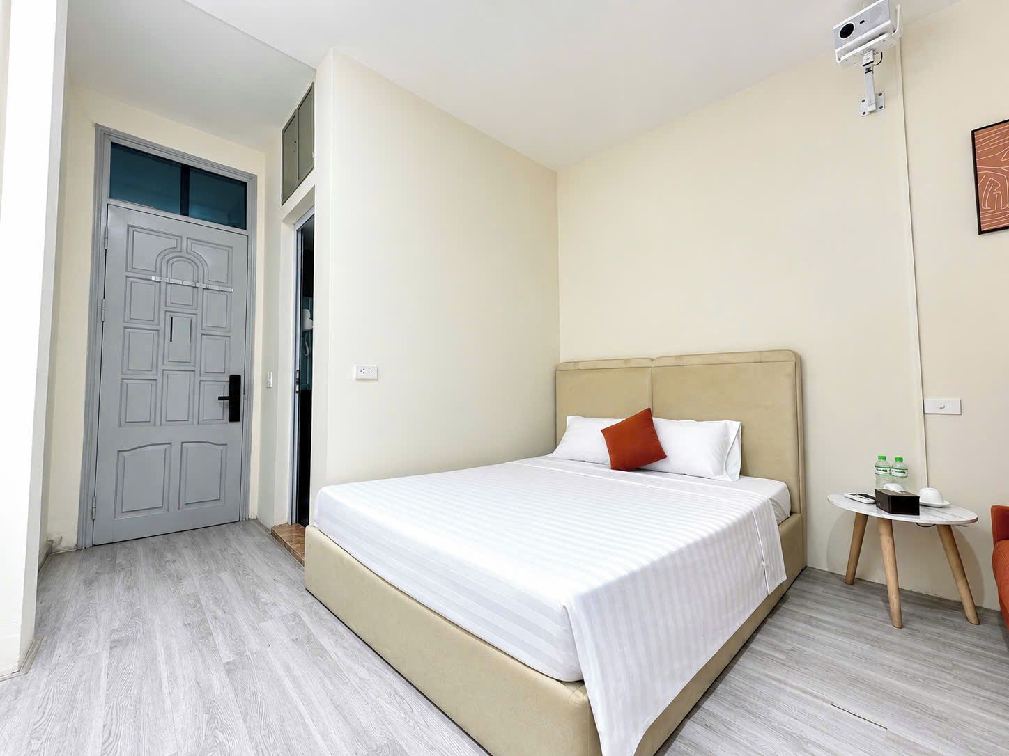 Une chambre d’hôtel avec un lit, une petite table ronde, une chaise et une porte.