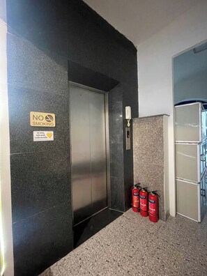 An elevator with a 'NO SMOKING' sign, a fire alarm, and two fire extinguishers on the floor. - Hanoi Aurelia Residence (Hanoi)