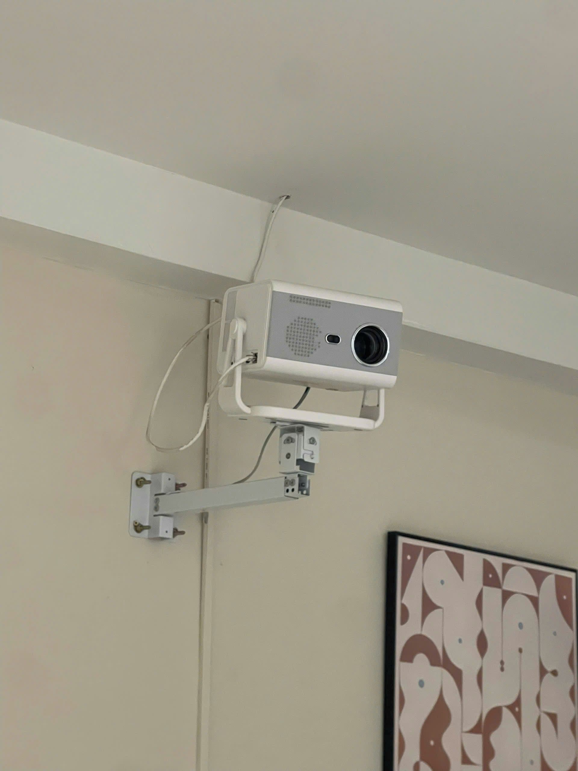 Un projecteur fixé au mur, relié à celui-ci par un câble.