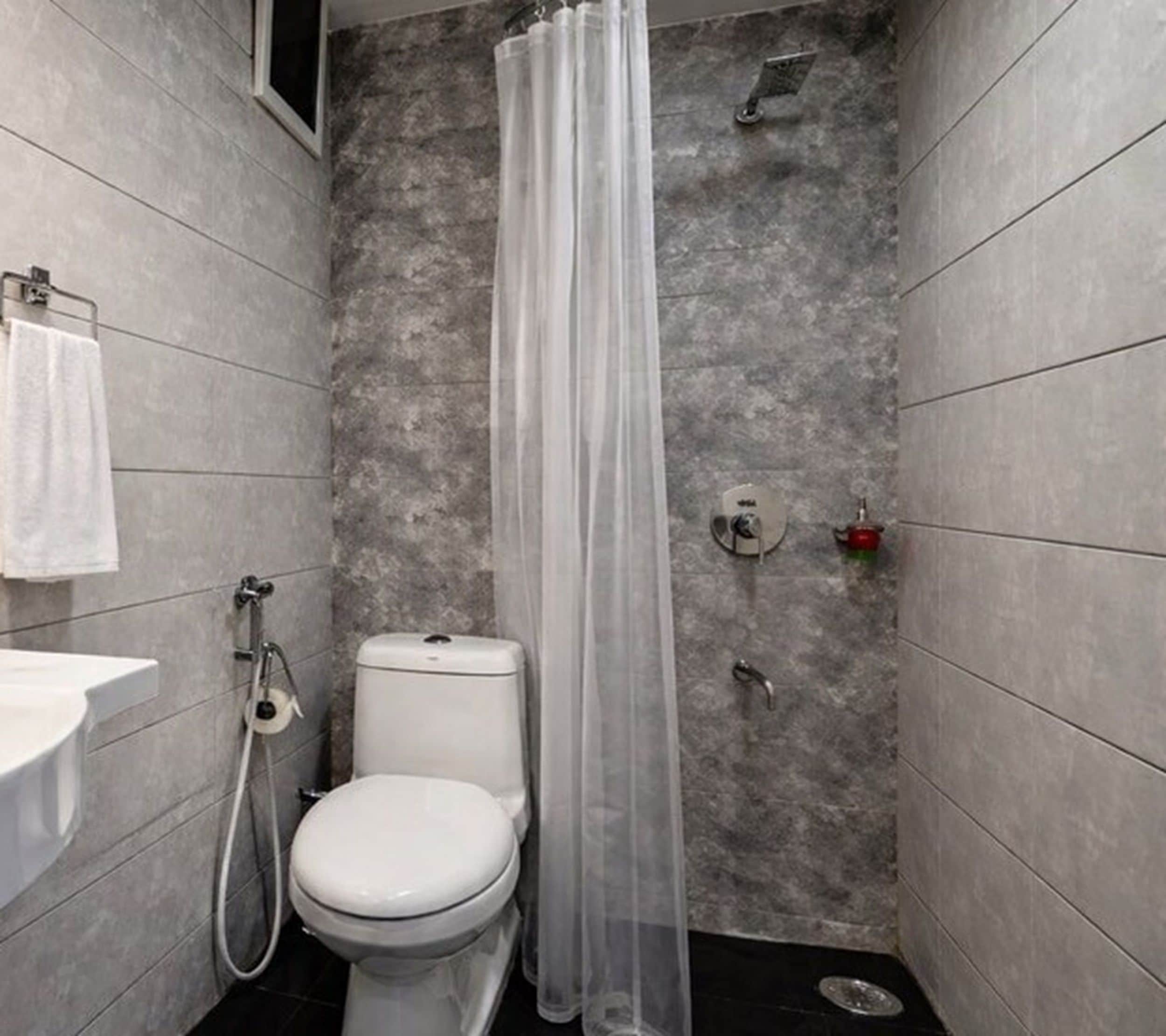 Un baño pequeño y moderno con inodoro, ducha y lavamanos.